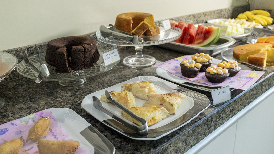 Buffet de café da manhã | Restaurante Planalto, Rurópolis – PA Buffet de café da manhã com bolos, frutas, salgados e folhados sobre uma bancada no Planalto Palace Hotel, em Rurópolis, Pará.