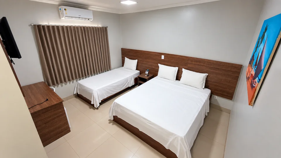 Suíte Tripla Casal do Planalto Palace Hotel em Rurópolis, com cama de casal, cama de solteiro, mesa de trabalho, frigobar e ar-condicionado.